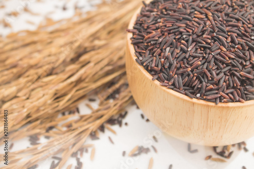 A Healthy Organic Unpolished Riceberry Grain Filled in a Wooden Bowl Placed Side by Side with Dry Rice Ears on a White Soft Background