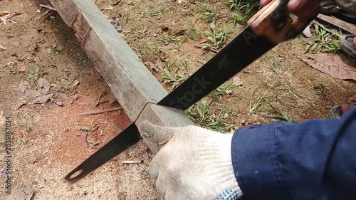 Man Cutting a Wooden Plank with a Handsaw Outdoors