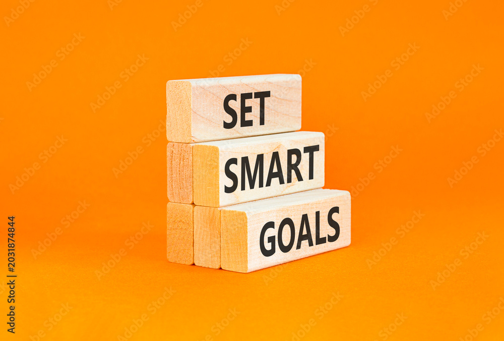 Naklejka premium Set smart goals words symbol. Concept words Set smart goals on beautiful wooden blocks. Beautiful orange background. Business and set smart goals concept. Copy space.