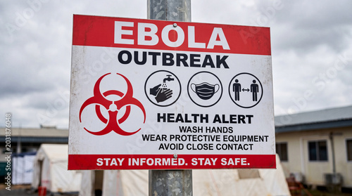 Ebola outbreak warning sign outdoors with biohazard symbol and public health safety instructions in an emergency quarantine environment