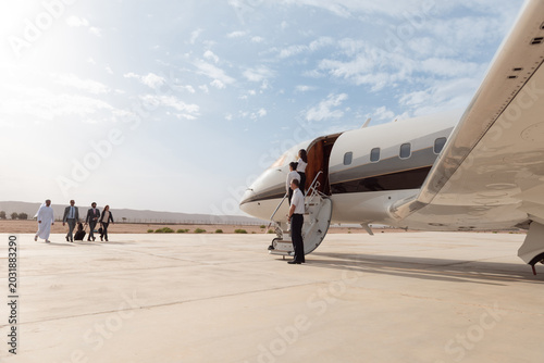Business executives boarding a private jet for luxury travel at a desert airport