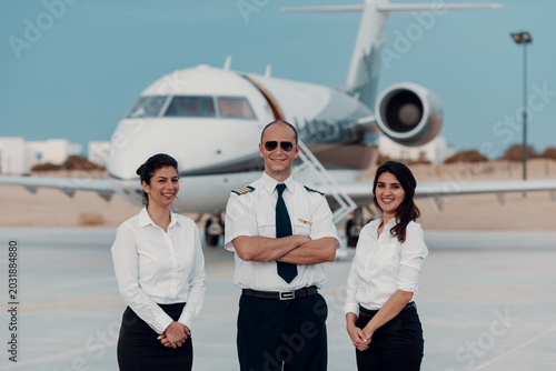 Fotografia Pilot and two crew members posing in front of private jet on airport tarmac for