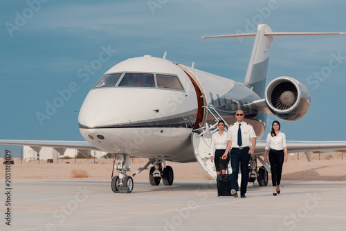 Obraz na płótnie Business pilot and flight crew walking confidently from private jet on airport t