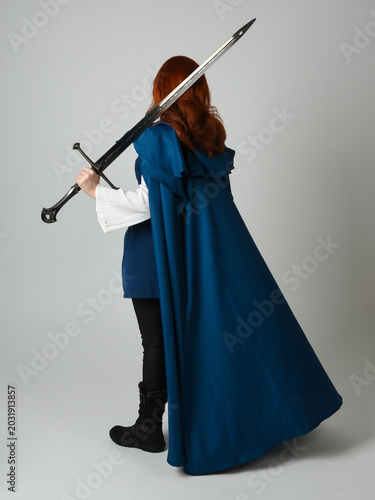 Foto full length portrait of female red head model wearing medieval fantasy warrior historical costume with blue cloak