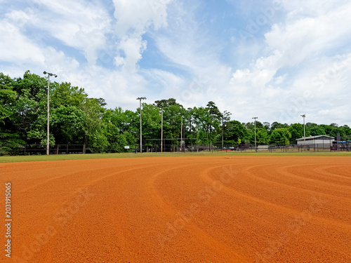 Tableau sur toile Well maintained baseball infield dirt with green trees background