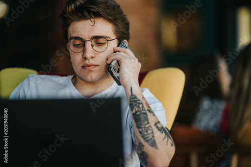 Foto Two teenage friends work on a laptop while one talks on a smartphone