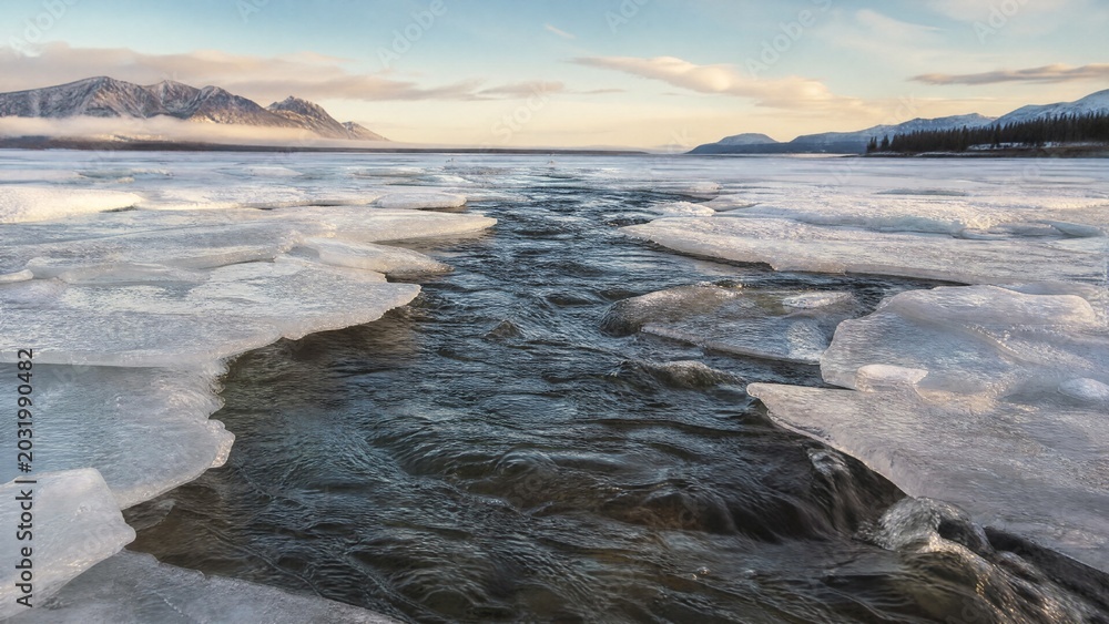 Fototapeta premium verglas. Landscape of a melting river breaking through ice in morning light. travel magazines, destination branding, designed for outdoor magazines and nature guides, drives exploration.