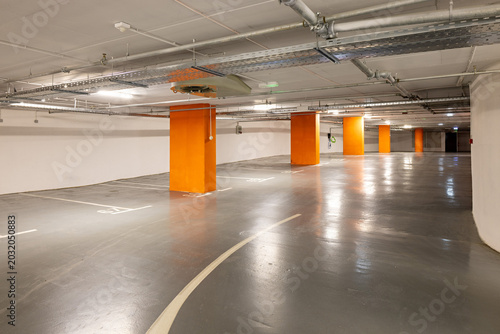 Clean underground parking garage with orange pillars and ventilation system
