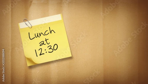 Yellow Sticky Note with Lunch at 12:30 Message on Brown Paper