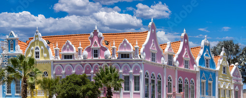 A wide panoramic shot of colorful pink yellow and blue Dutch colonial style architectural facades in downtown Oranjestad Aruba Caribbean vacation destination