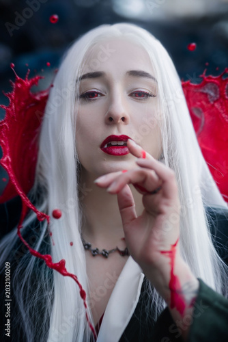 A gothic vampire with red eyes and blood splatter. Portrait at night.