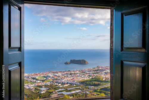Ocean view of Vila Franca do Campo and its volcanic islet framed through an open door at Nossa Senhora da Paz sanctuary in Azores, Portugal.