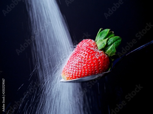   Concept of sugar pouring on a strawberry.