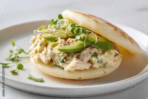 Delicious Reina Pepiada Arepa with Avocado and Chicken on White Plate in Natural Light Setting