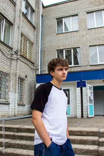 Bild auf Leinwand portrait of a dark-haired teenage boy on street in the city, hands in jeans pock