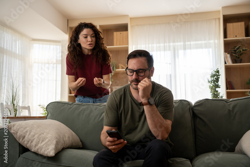 Jealous woman spying on partner’s phone in tense relationship moment at home