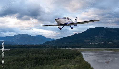 Small Single-Engine Airplane Flying Over Forested Mountains With Dramatic Cloudy Sky