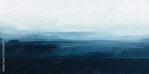 A beautiful summer morning landscape shows thick mist and fog rolling over the calm water surface of a blue river as the sun begins to light up the horizon and cloudy sky