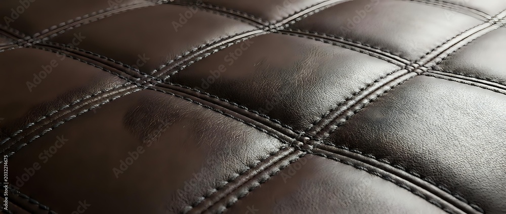 Fototapeta premium Brown leather upholstery with diamond quilted pattern and decorative stitching for luxury furniture and interior design applications.