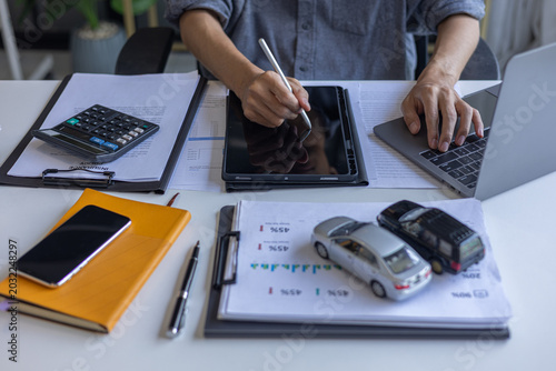 Картината върху платно Person Signing Car Purchase Agreement Online in Tablet with Model Vehicles on Table