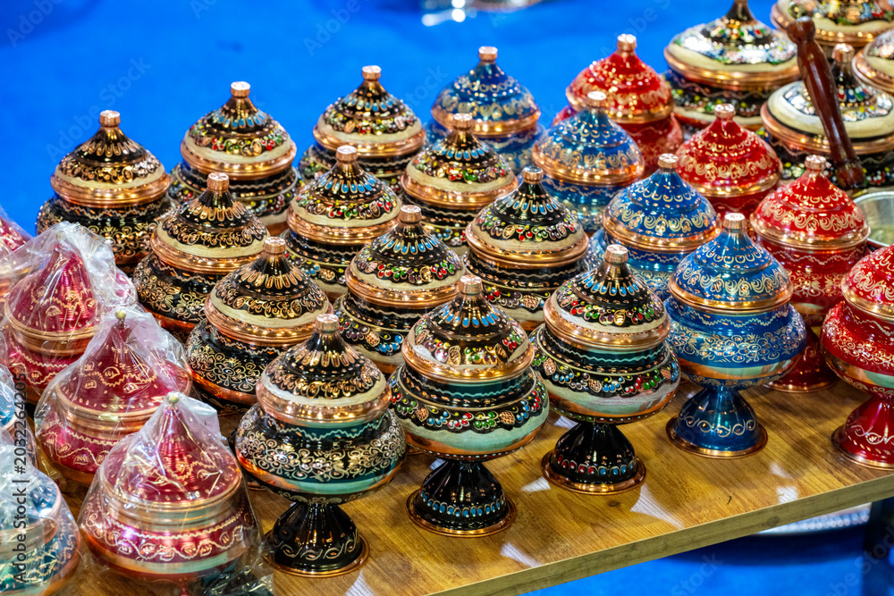 Fototapeta premium Metal coffee cezve with decorative oriental pattern on the shop window. Household items copper items for sale. Cupric coffe epots at the bazaar in Antalya Turkey. Turkish coffee pots. Metal coffee cez
