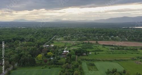 Red Hook, NY, USA - 05-20-2026  Aerial hyperlapse video of a small town nestled within a vast expanse of lush green forest under a partly cloudy sky.