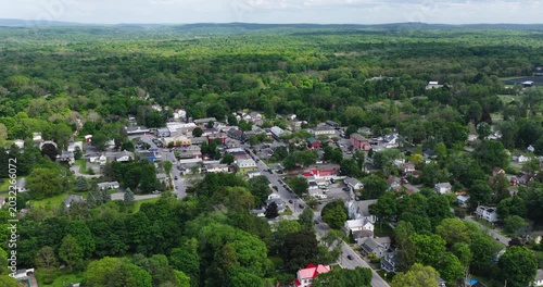 Red Hook, NY, USA - 05-20-2026  Aerial video of Red Hook, NY, a small upstate town nestled within a vast expanse of lush green forest under a partly cloudy sky.