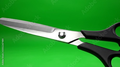 Close up of scissors blades against a bright green backdrop