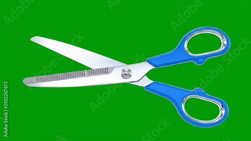 Close up of scissors with blue handles and sharp blades on a green backdrop