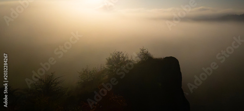 Quadro su tela Autumn sunrise above the Hlubočepy Rocks in Prague, Czech Republic, with golden sun rays piercing dense morning fog and creating a peaceful atmospheric landscape