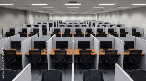 Academic testing center featuring long rows of private examination cubicles with grey ergonomic desks interior.