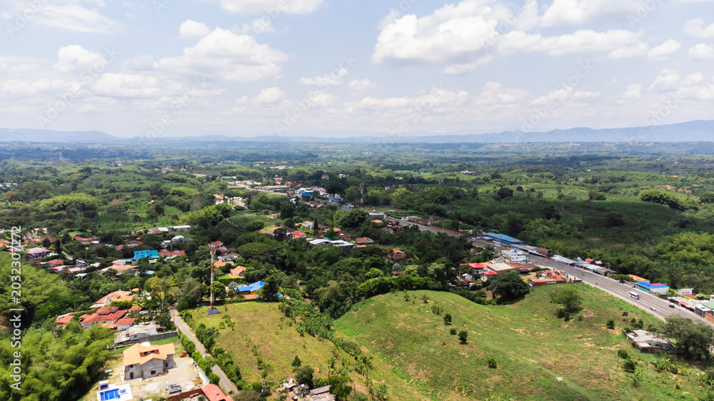 Obraz premium Aerial view Green area near Armenia, quindio Colombia, Sunny day forest area, nature tree zone, fliying over road, building background 4k