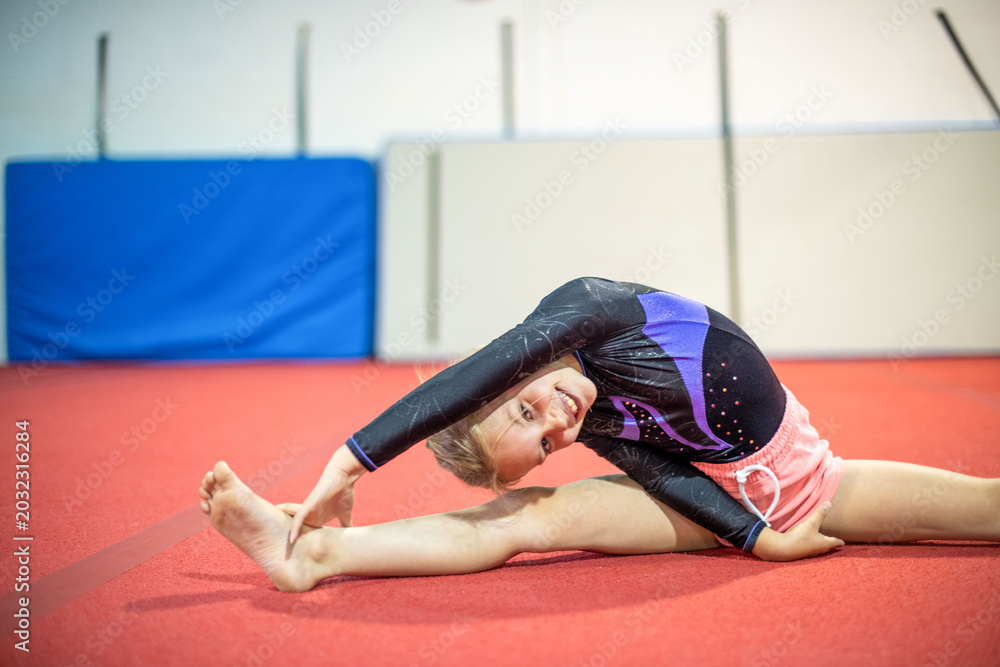 Obraz premium Young gymnast stretching on mat.