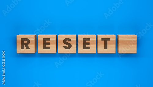 Slika na platnu Reset Button on Blue Background: Wooden blocks with the word RESET are neatly arranged against a vibrant blue background, symbolizing a fresh start or a new beginning