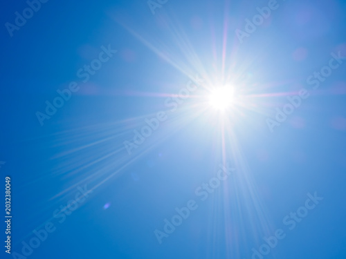 青空に強く輝く夏の太陽　猛暑と紫外線対策のイメージ