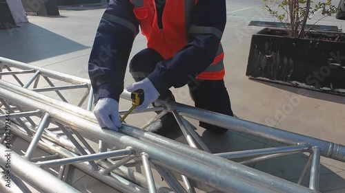 Technician Measuring Metal Structure With Tape Measure in Industrial Environment