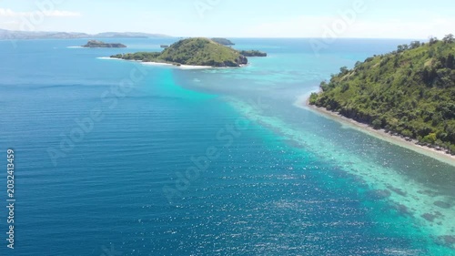 Panoramic aerial view of the 17 Islands Marine Park near Riung, Flores, Indonesia, featuring turquoise coral reefs, tropical islets, and deep blue ocean under a bright sky