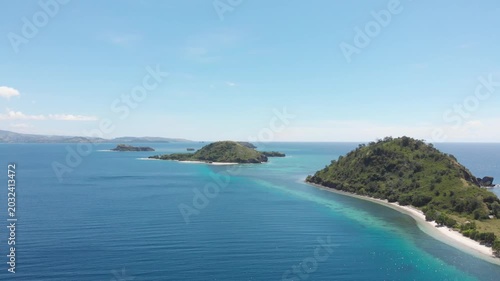Panoramic aerial view of the 17 Islands Marine Park near Riung, Flores, Indonesia, featuring turquoise coral reefs, tropical islets, and deep blue ocean under a bright sky