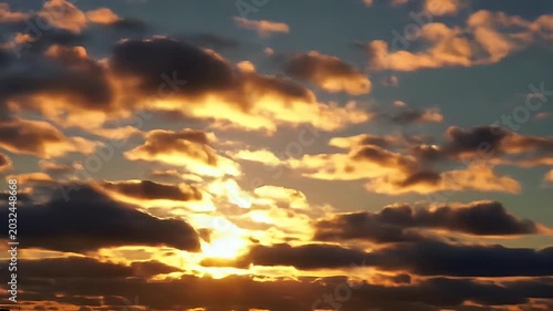 Golden clouds illuminated by sunset glow, casting dramatic shadows across the sky