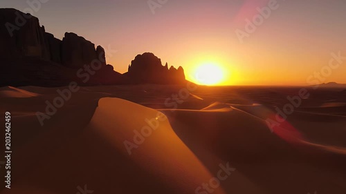 Golden desert dunes glow under a dramatic sunset with rock formations