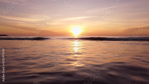 Sun setting over ocean with gentle waves reflecting golden light