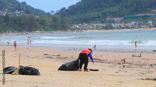 Thai locals cleaning massive ocean trash from polluted tropical Patong Beach Thailand.