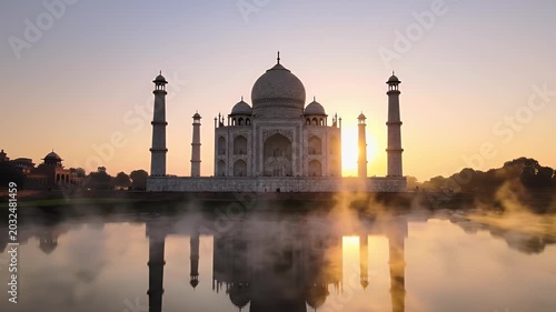 Marble mausoleum with minarets reflected in misty water at sunrise