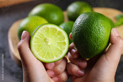 Fotografie Fresh Hainan Limes in Hands - Seedless Citrus Fruit for Lemonade and Cooking