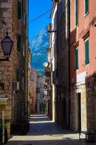 Cozy old alley in Makarska surrounded by historic stone buildings and dramatic Dalmatian mountains. A romantic European travel destination perfect for authentic local experience, cultural tourism.