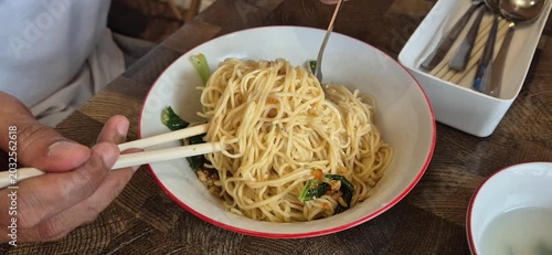 A person is stirring noodles in a bowl