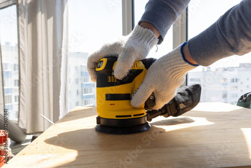 Random orbital sander finishing curved wooden panel during carpentry repair