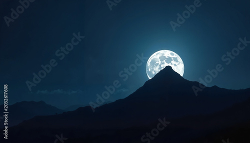 Full moon rising over mountain peak at night in dark sky  