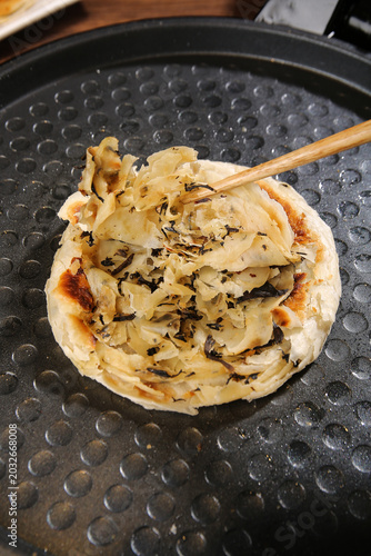 Картината върху платно Traditional Chinese Scallion Pancake Cooking in Non-Stick Pan with Wooden Spatul