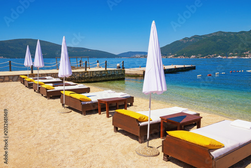 Beach vacations, waiting for summer. Coast of Bay of Kotor with chaise lounges and beach umbrellas. Montenegro, Tivat